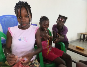 Girls work on bags made from soda tops in the Moving Sands project.